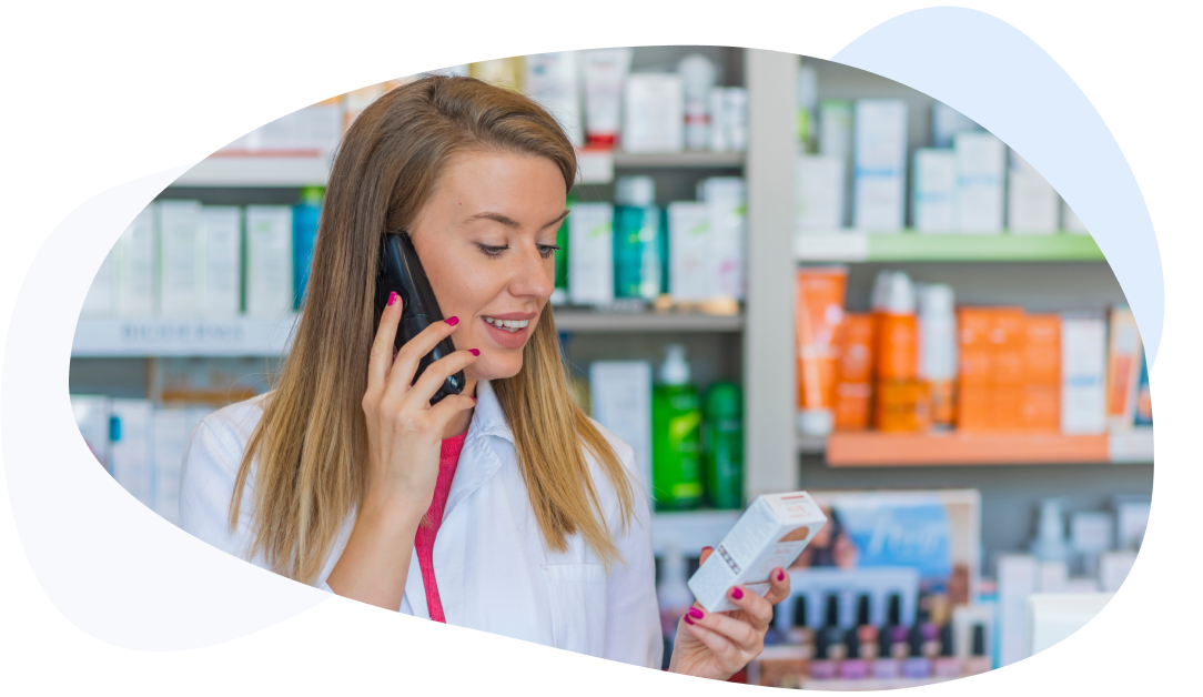Female pharmacist talks on the phone while holding a medication box.
