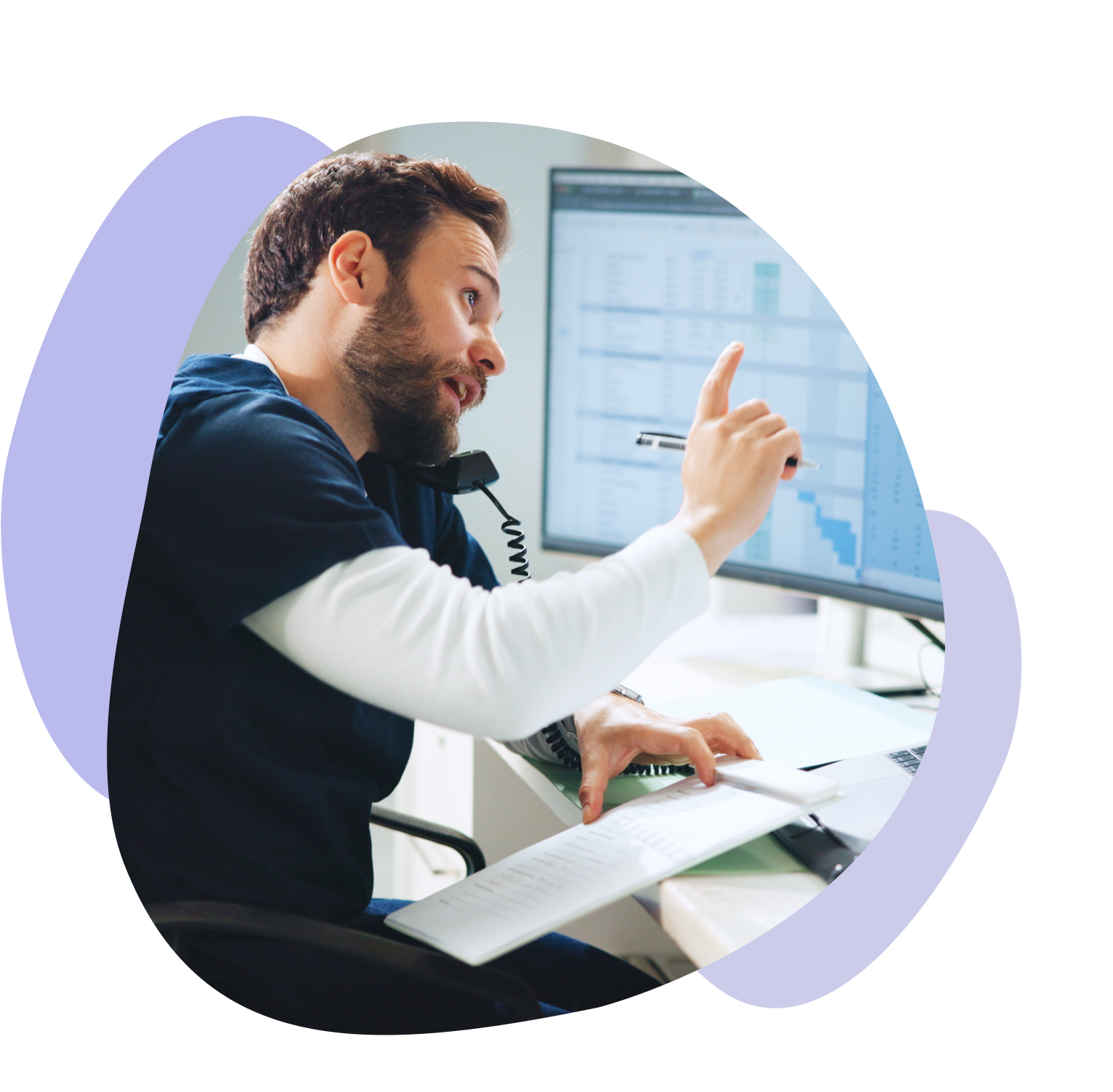 Healthcare worker at a desk holds a phone between shoulder and ear, coordinating multiple tasks.